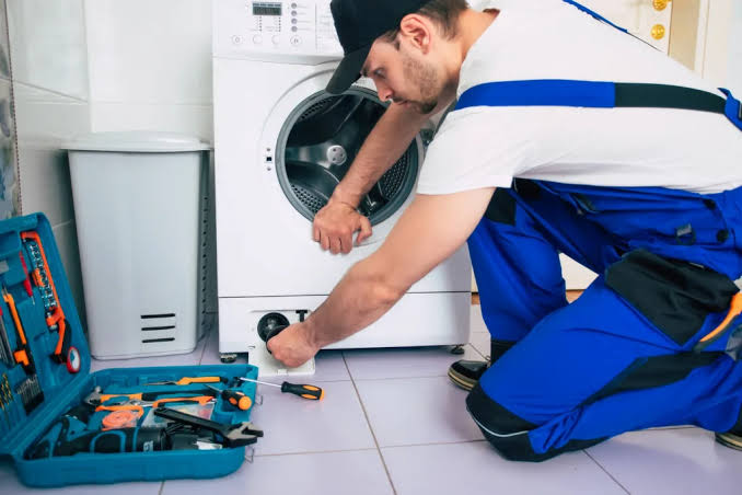 Technician inspecting a washing machine during a repair visit